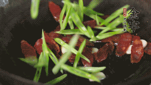 先后下香腸片、四季豆絲均勻翻炒，加適量清水燜煮一下。