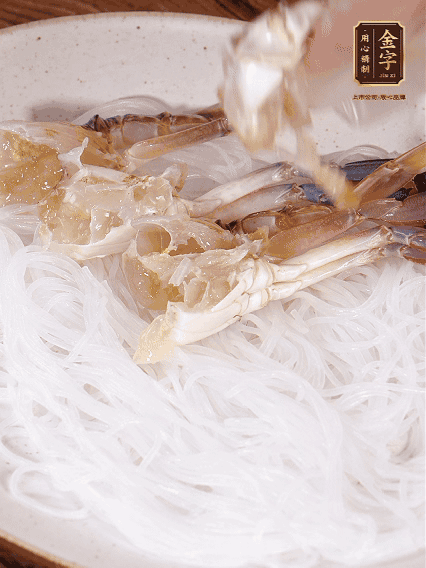 盤(pán)底墊上粉絲，擺上梭子蟹、火腿片，撒姜粒，淋上蒸魚(yú)豉油、花雕酒調(diào)味腌制15分鐘